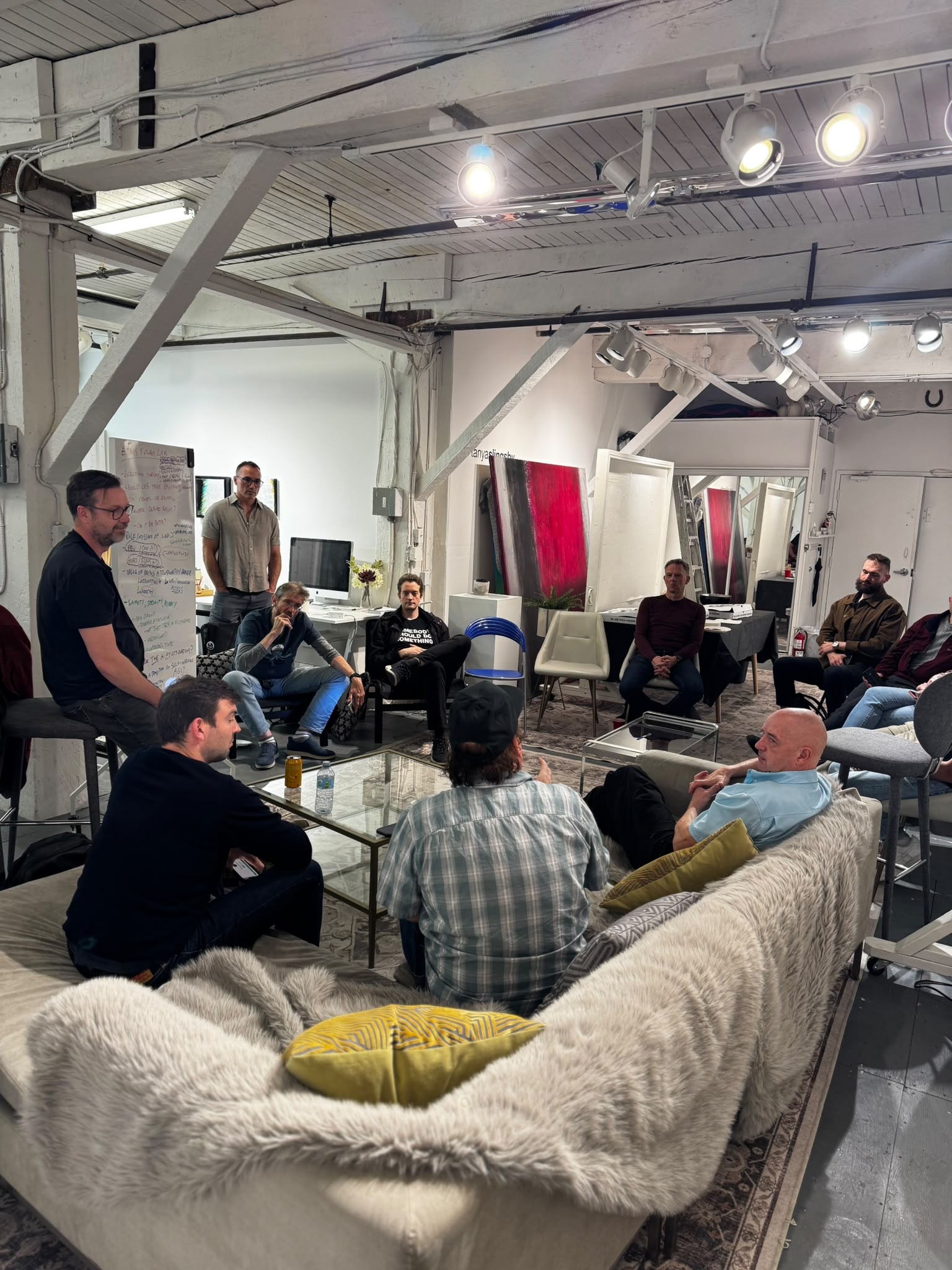 Participants listen and talk around low tables in the studio.